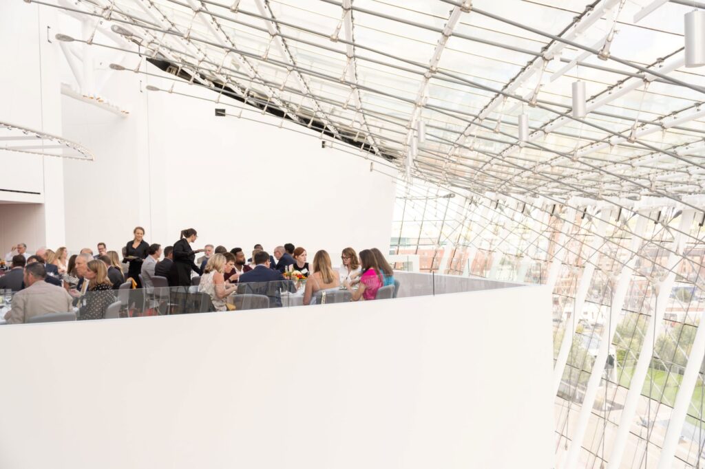 A groups of people sit at round tables on a balcony