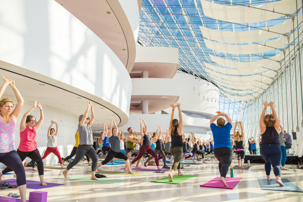 People participating in a group yoga session at Kauffman Center in a modern indoor space with large windows and natural light.
